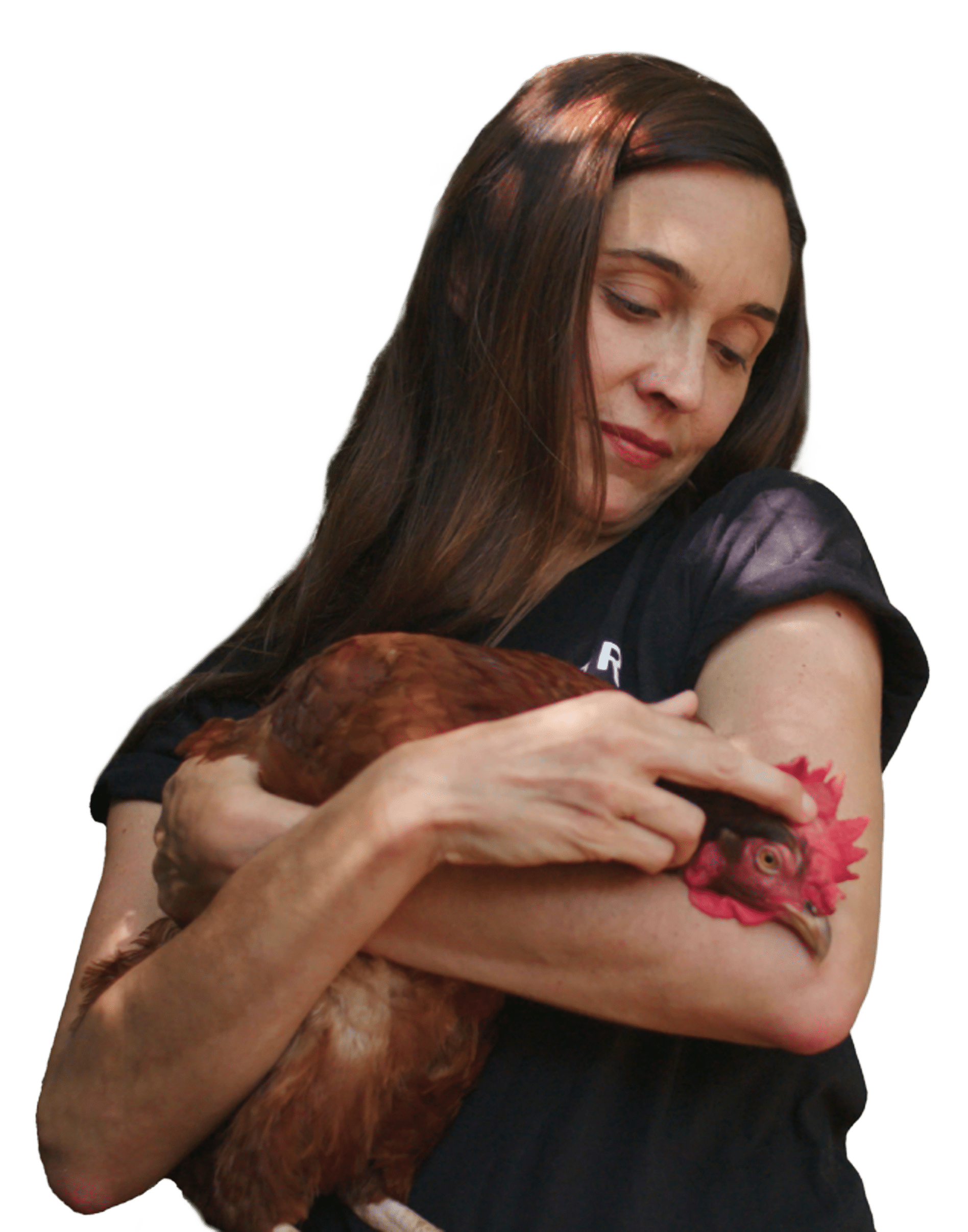 Leah Garcés holding a brown hen in her arms and smiling gently.