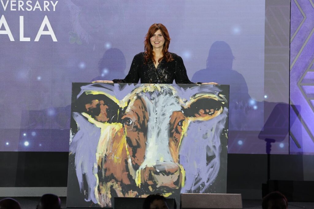 Speed painter showing portrait of a cow she painted at Mercy For Animals 25th Anniversary Gala